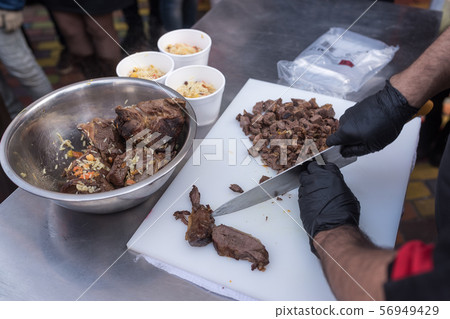 Hand holds bowl with meat and rice. 56949429