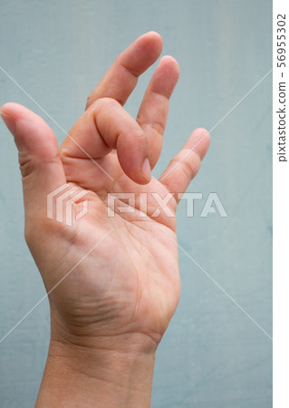Trigger Finger lock on index finger of woman's side left hand, Suffering from pain, On Blue-grey colour background, Close up & Macro shot, Office syndrome, Health care concept Trigger Finger lock on index finger of woman's side left hand, Suffering from pain, On Blue-grey colour background, Close up & Macro shot, Office syndrome, Health care concept 56955302