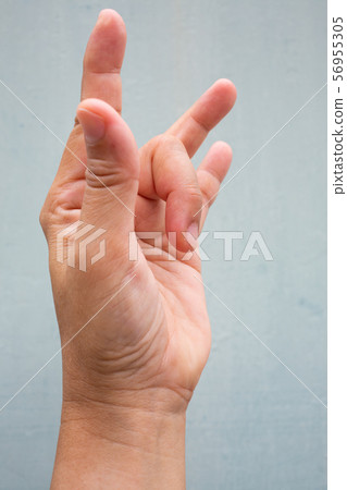 Trigger Finger lock on middle finger of woman's side left hand, Suffering from pain, On Blue-grey colour background, Close up & Macro shot, Office syndrome, Health care concept Trigger Finger lock on middle finger of woman's side left hand, Suffering from pain, On Blue-grey colour background, Close up & Macro shot, Office syndrome, Health care concept 56955305