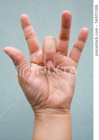 Trigger Finger lock on middle finger of woman's front left hand, Suffering from pain, On Blue-grey colour background, Close up & Macro shot, Office syndrome, Health care concept Trigger Finger lock on middle finger of woman's front left hand, Suffering from pain, On Blue-grey colour background, Close up & Macro shot, Office syndrome, Health care concept 56955306