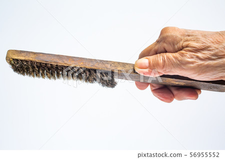 Senior Woman's right hand holding old wire brush isolated on white background, Construction building and repair tool concept 56955552