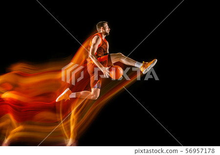 Young caucasian basketball player against dark background in mixed light Young caucasian basketball player against dark background in mixed light 56957178