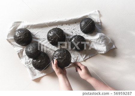 Black bread buns. Slicing black hamburger bread 56959287