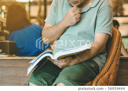 Asian man read a book in a coffee shop. Asian man read a book in a coffee shop. 56959444