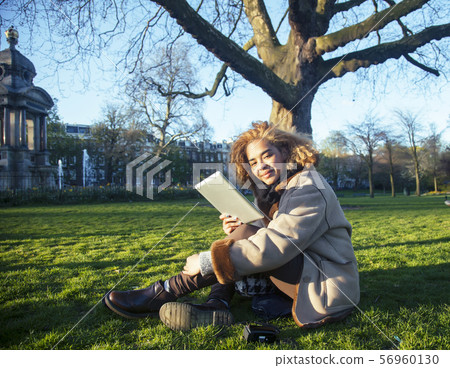 young pretty african american girl with curly hair making photo on a tablet, lifestyle people 56960130