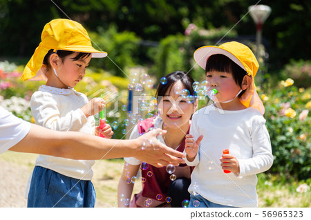 Childcare teachers and children taking a walk 56965323