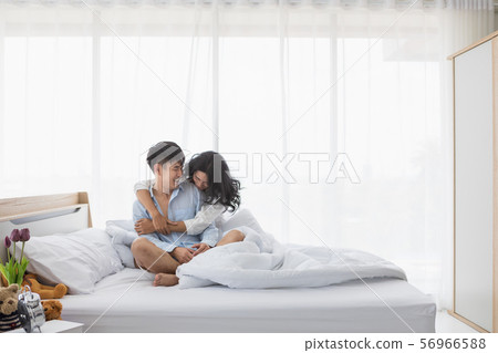 Couple sitting on bed, they hug each other by 56966588