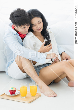 Asian couple sitting on the floor in the bedroom.. Asian couple sitting on the floor in the bedroom.. 56966589