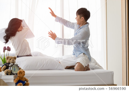 Asian couple sits on bed, They have pillow fight.. Asian couple sits on bed, They have pillow fight.. 56966590