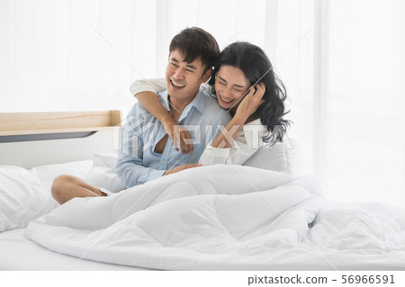 Couple sits on bed, they hug each other by love.. Couple sits on bed, they hug each other by love.. 56966591