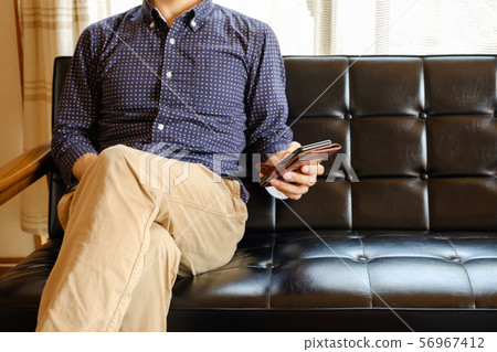 A man who operates a smartphone on his sofa at home 56967412