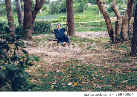 old mature elderly senior woman sitting on swing 56970004