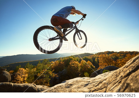 Professional sportsman cyclist jump on trial bike on boulder 56970625
