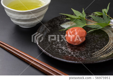 Chopsticks, plum blossoms and autumn leaves Japanese tea copy space on a high-quality black plate on a black background 56973951