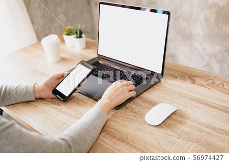 Asian woman holding phone and using computer Asian woman holding phone and using computer 56974427