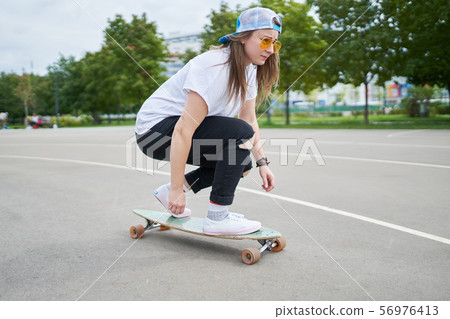 Portrait of sporty brunette riding skateboard outdoors 56976413