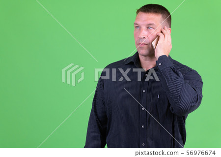 Mature macho businessman thinking while talking on the phone 56976674