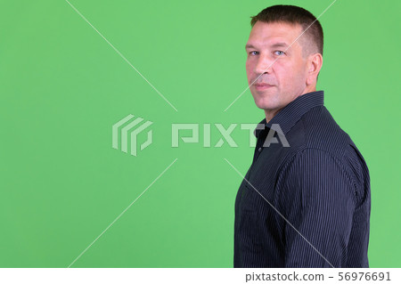 Profile view of mature macho businessman looking at camera 56976691