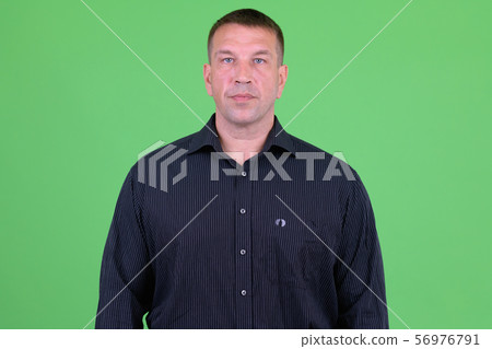 Portrait of mature macho businessman looking at camera 56976791