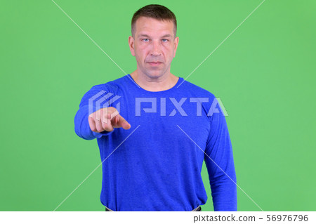 Portrait of macho mature man pointing at camera 56976796