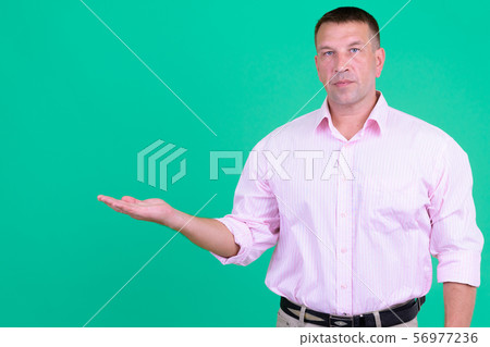 Mature macho businessman with pink shirt showing something Mature macho businessman with pink shirt showing something 56977236