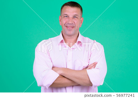 Happy mature macho businessman smiling with arms crossed 56977241