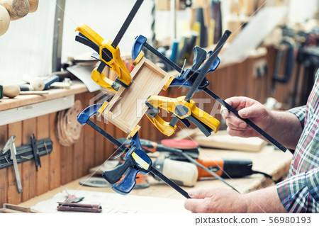 Senior carpenter glueing wooden craft surface and 56980193