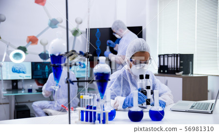 Female scientist in protection equipment adjusting her microscope 56981310
