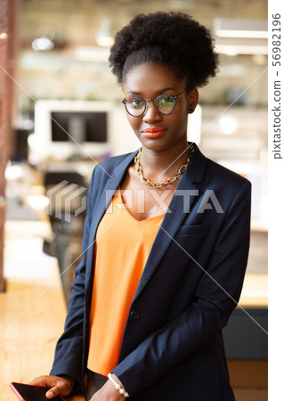 Dark-eyed curly woman with bright lips standing near table 56982196