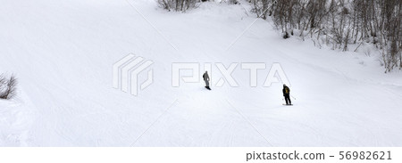Skier and snowboarder on ski slope at gray winter Skier and snowboarder on ski slope at gray winter 56982621