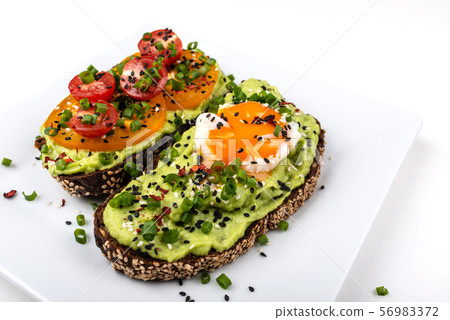 Sandwiches with avocado guacomole, egg and tomatoes, green leek and sesame seeds. Healthy breakfast 56983372