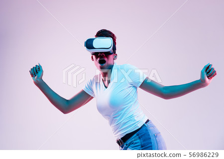 Young african-american woman's using VR-glasses in neon light Young african-american woman's using VR-glasses in neon light 56986229