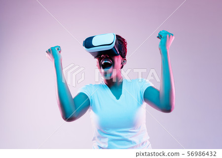 Young african-american woman's using VR-glasses in neon light Young african-american woman's using VR-glasses in neon light 56986432
