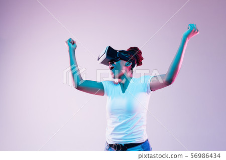 Young african-american woman's using VR-glasses in neon light 56986434