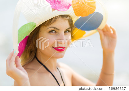 A brunette girl holds a hat on her head. A brunette girl holds a hat on her head. 56986817