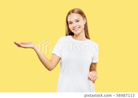 Caucasian young woman's half-length portrait on yellow background Caucasian young woman's half-length portrait on yellow background 56987113