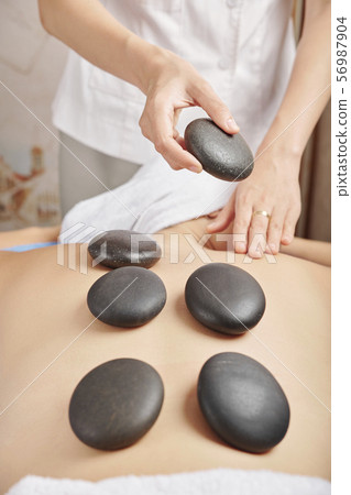 Woman receving hot stone massage Woman receving hot stone massage 56987904