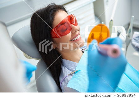 Dentist is treating teeth of young lady 56988954