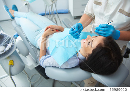 Male dentist examining teeth of happy woman 56989020