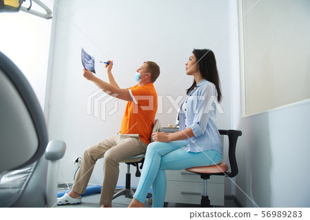 Woman and male dentist looking at results of orthopantomogram 56989283