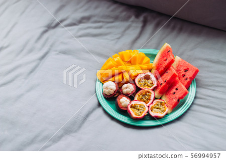 Plate with tropical fruit in grey bed, breakfast 56994957