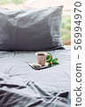pink cup coffee, donut, flower on grey bed. pillow 56994970