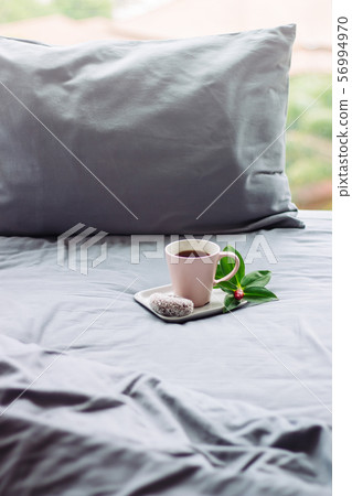 pink cup coffee, donut, flower on grey bed. pillow 56994970