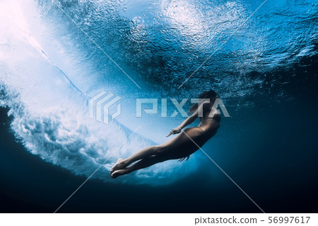 Woman in bikini dive without surfboard underwater with ocean wave. Duck dive under barrel wave Woman in bikini dive without surfboard underwater with ocean wave. Duck dive under barrel wave 56997617