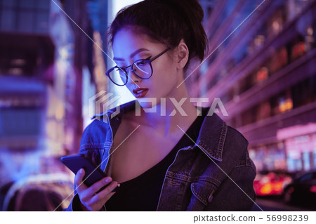 Woman Using a Smartphone in the City at Night 56998239