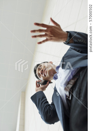 Gesturing businessman calling on phone 57000502
