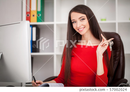 Happy realtor woman showing keys. Business women real estate agent holding house and house key Happy realtor woman showing keys. Business women real estate agent holding house and house key 57002024