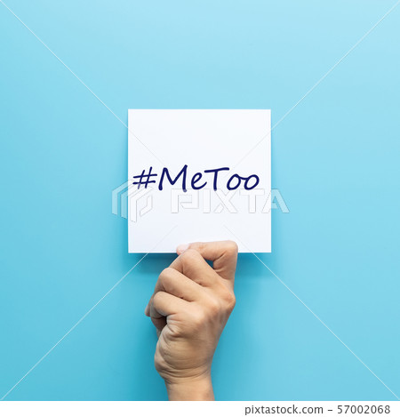 hashtag #MeToo on white paper in hand isolated on blue background. #MeToo is a campaign for movement against sexual harassment and sexual assault. 57002068