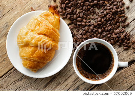 continental breakfast with fresh croissant and hot coffee on wooden background, decoration with coffee bean continental breakfast with fresh croissant and hot coffee on wooden background, decoration with coffee bean 57002069