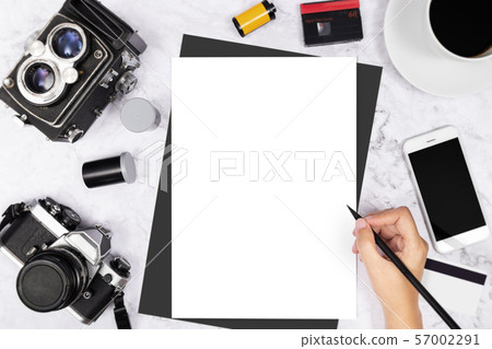 flat lay hand writing in a blank white page notebook decorated with vintage camera and photography tool on white marble background 57002291